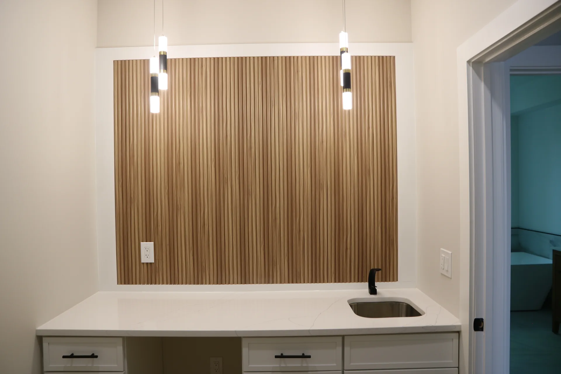 Built-in wet bar with wood slat accent wall and quartz counter
