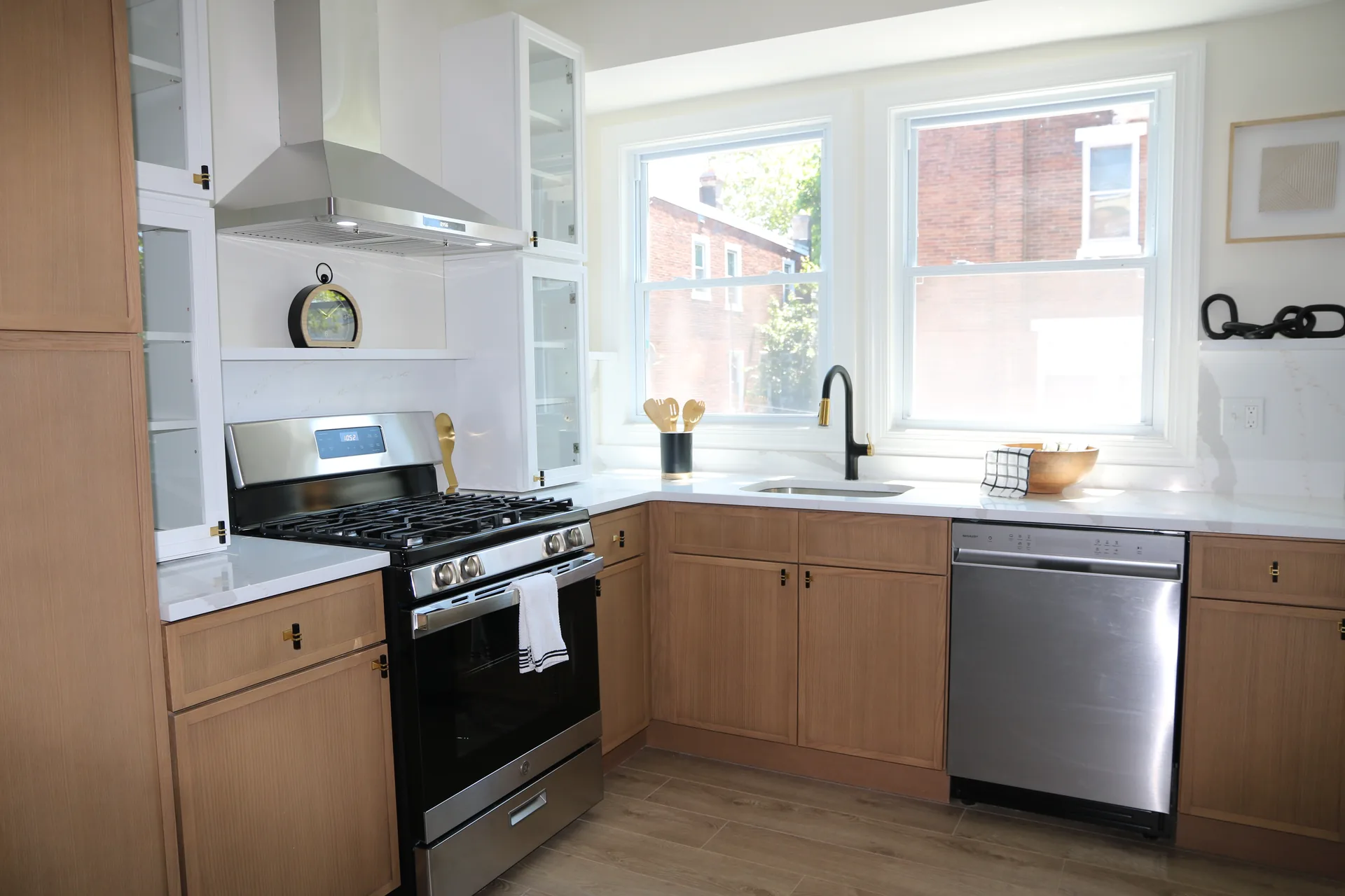 Corner kitchen with stainless hood, gas range, and double windows