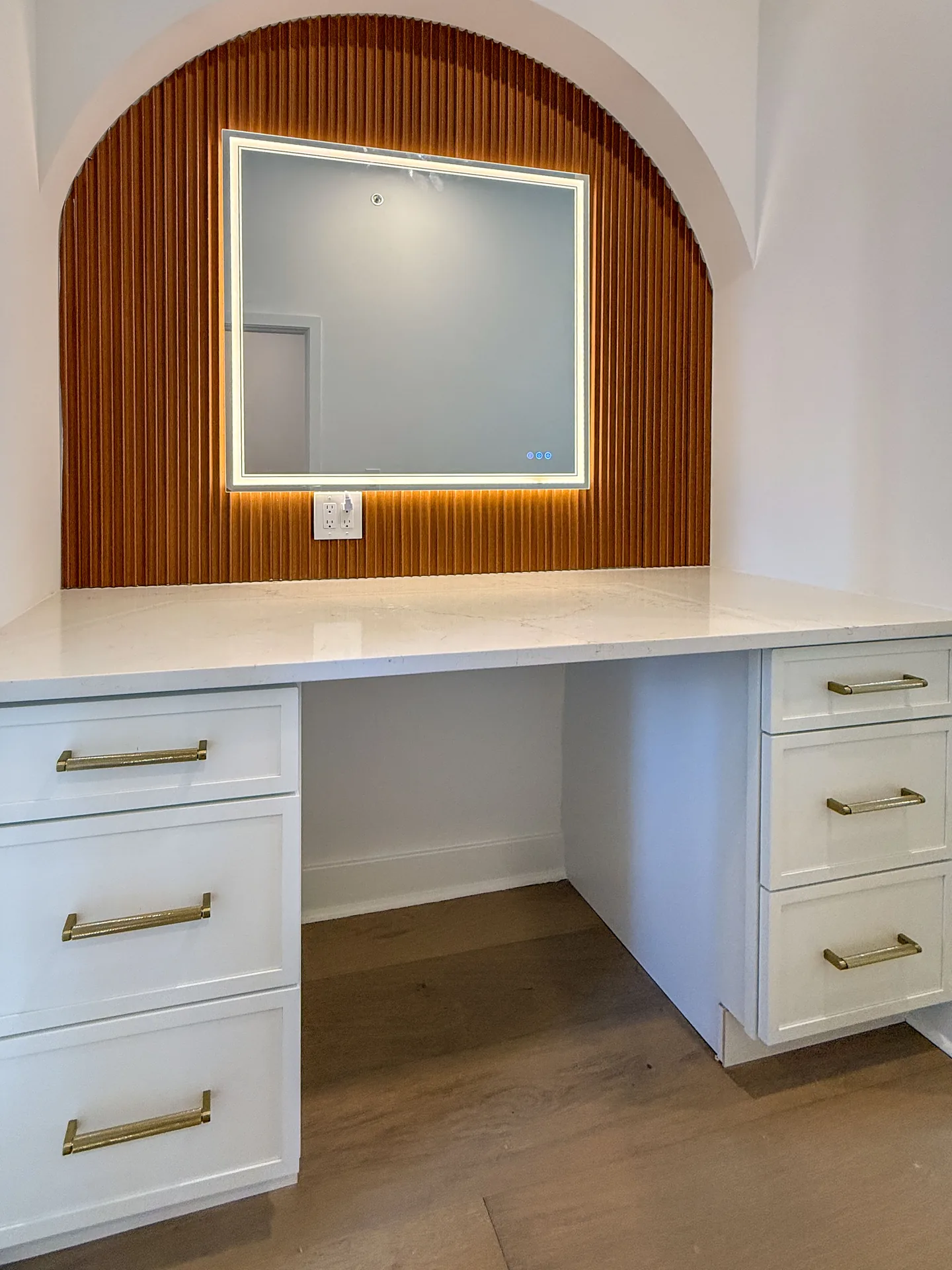 Arched vanity nook with fluted wood panelling and backlit mirror