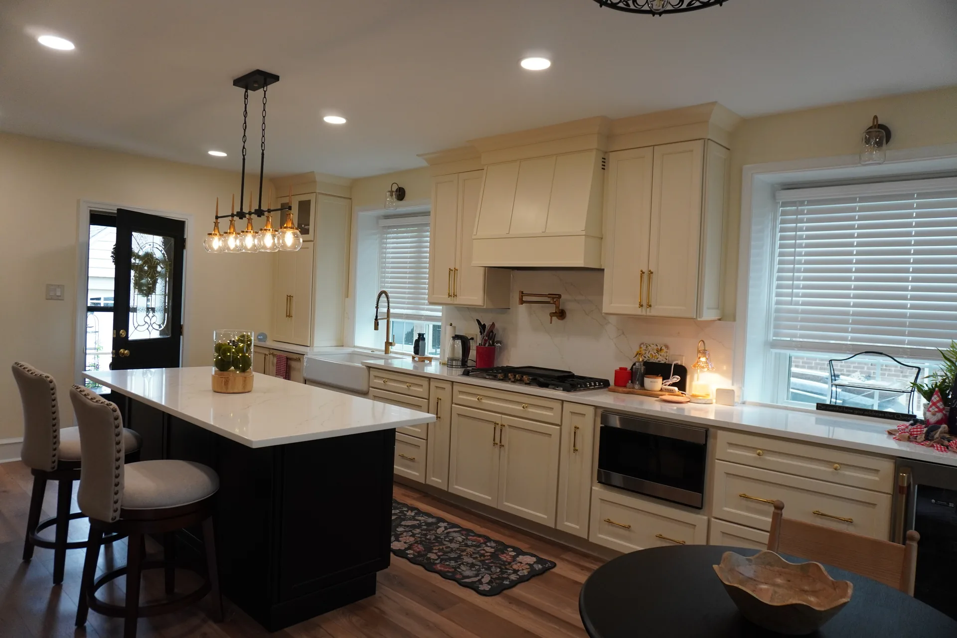 Full kitchen remodel with cream cabinets, black island, and pendant lighting