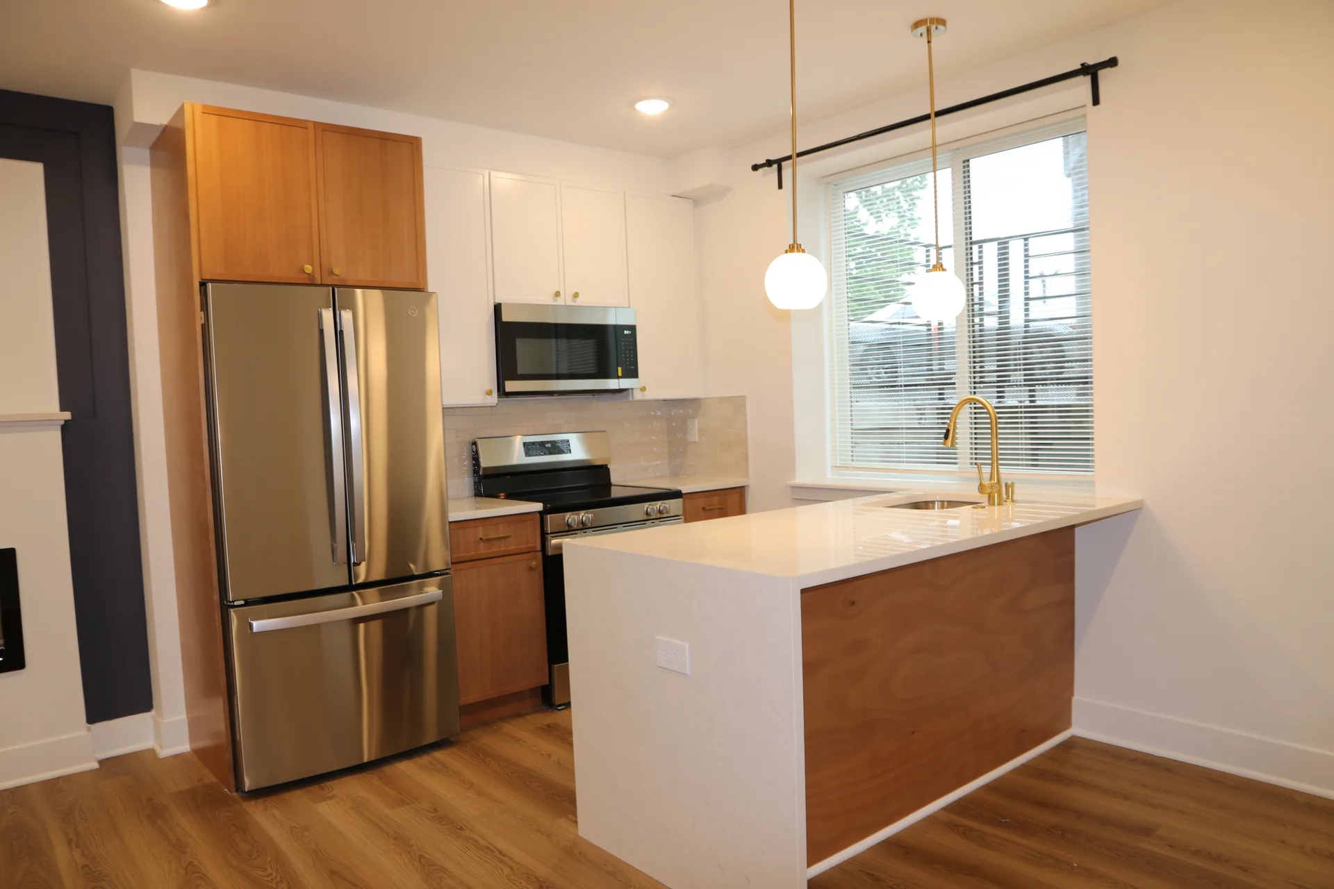 Apartment kitchen with wood island, white counters, and gold faucet