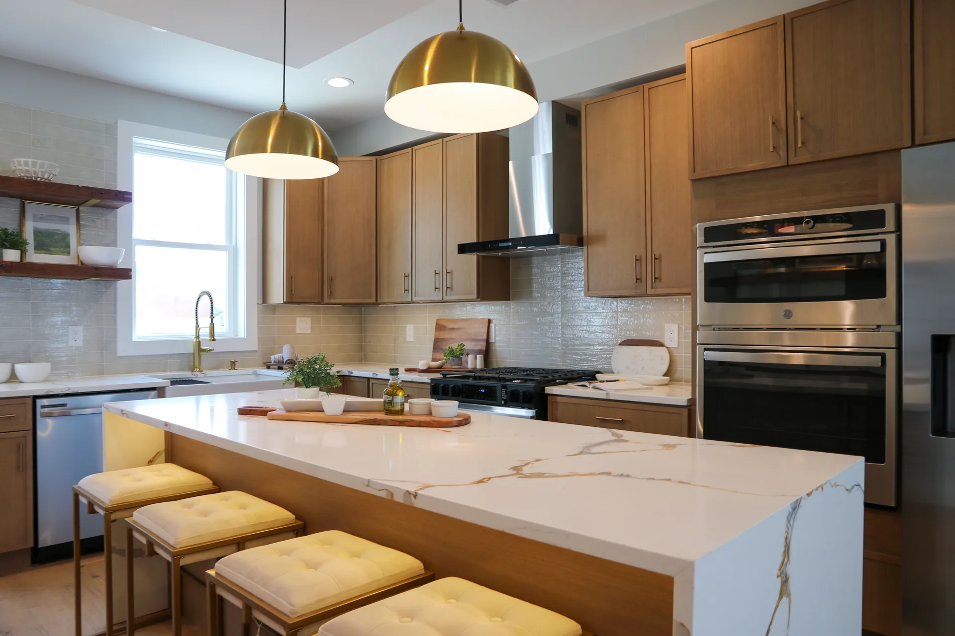 Calacatta quartz island with brass pendant lights and oak cabinetry