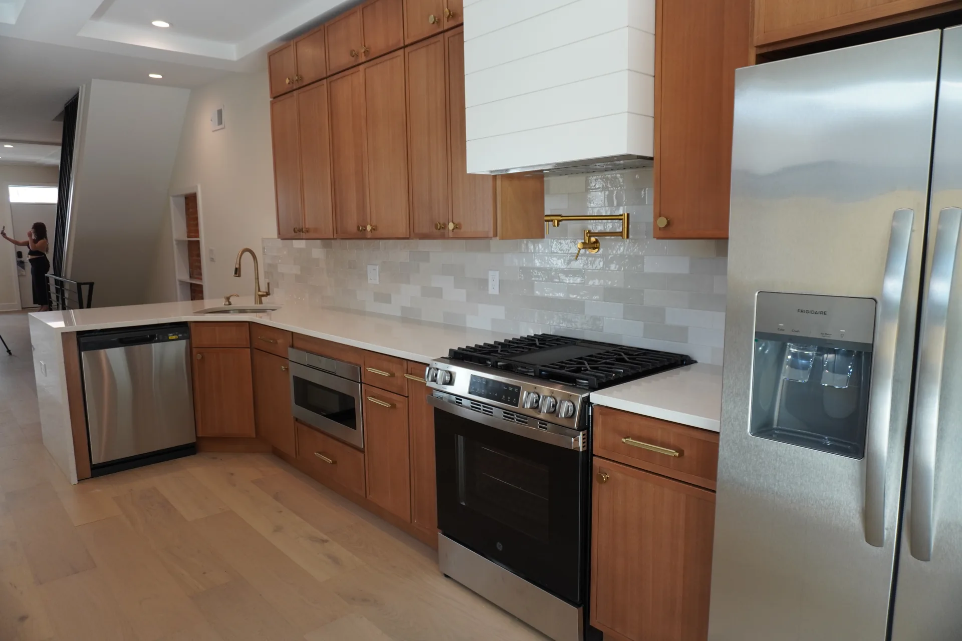 Warm wood kitchen with white shiplap hood and glazed tile backsplash
