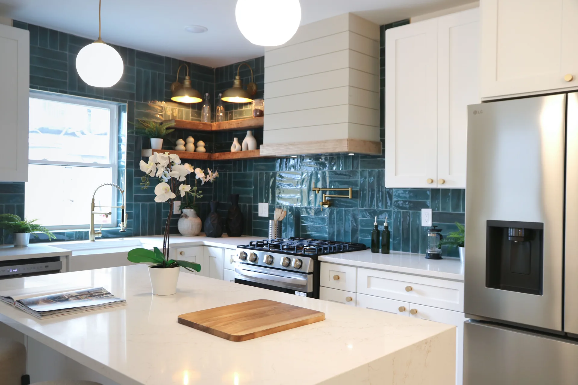Designer kitchen with teal tile walls, shiplap hood, and brass accents