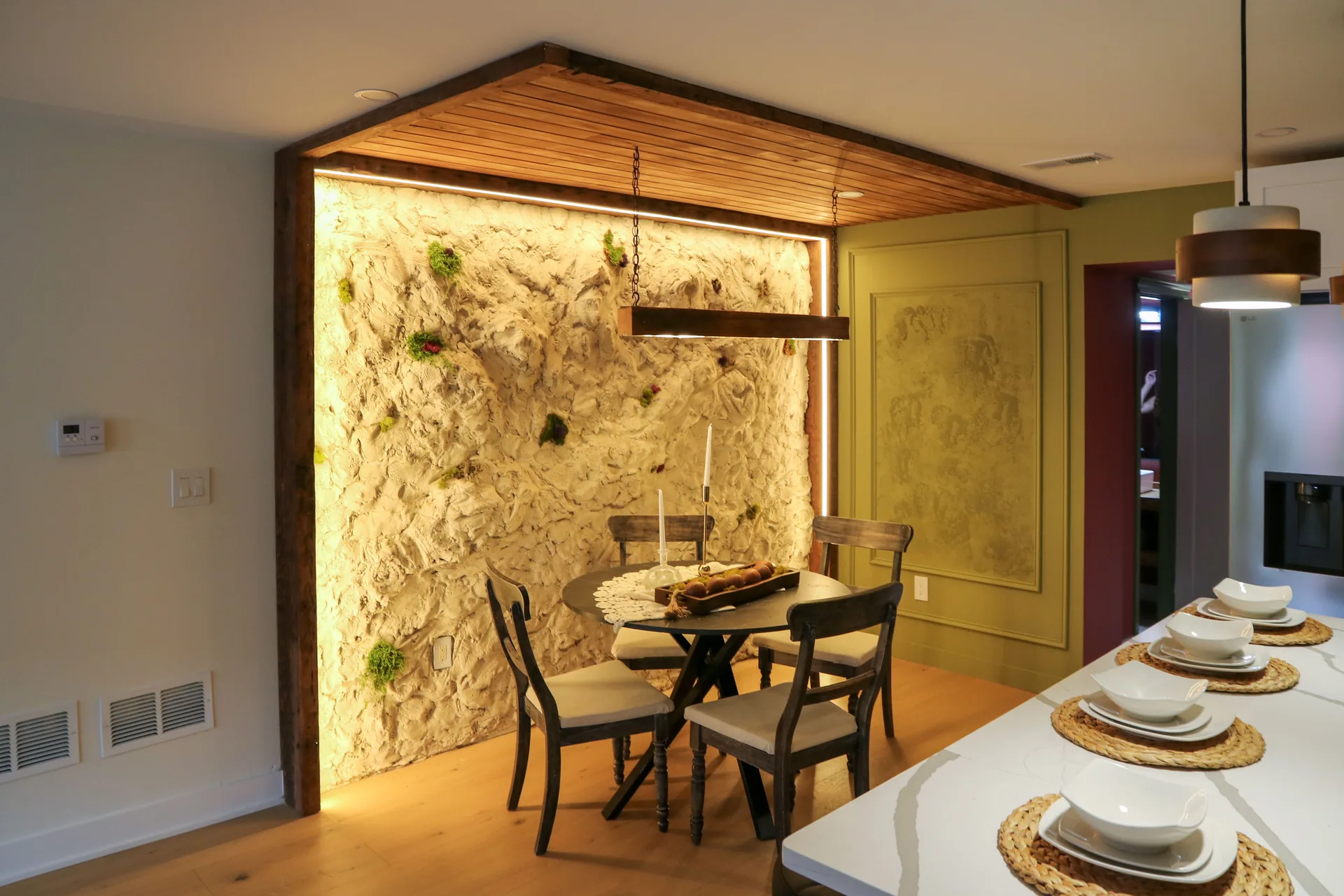Dining nook with sculpted stone accent wall and custom wood ceiling detail
