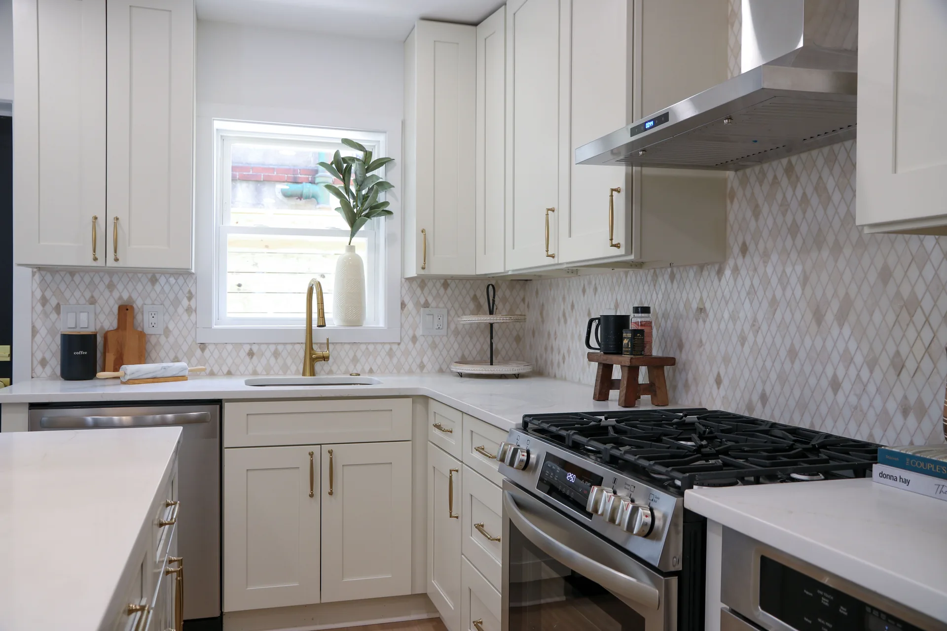 White kitchen with mosaic backsplash, gold hardware, and window over sink