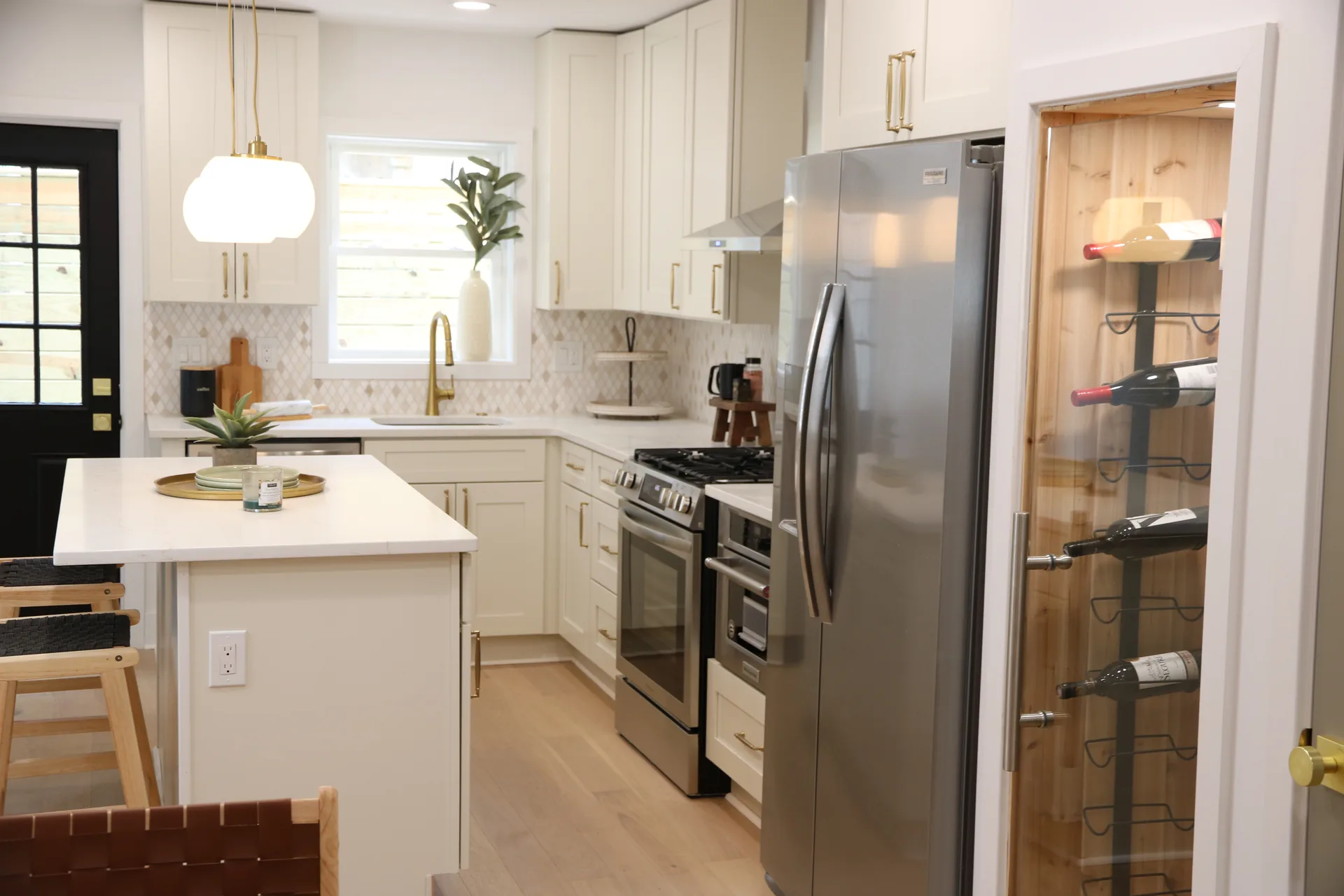 L-shaped white kitchen with quartz island and stainless appliances