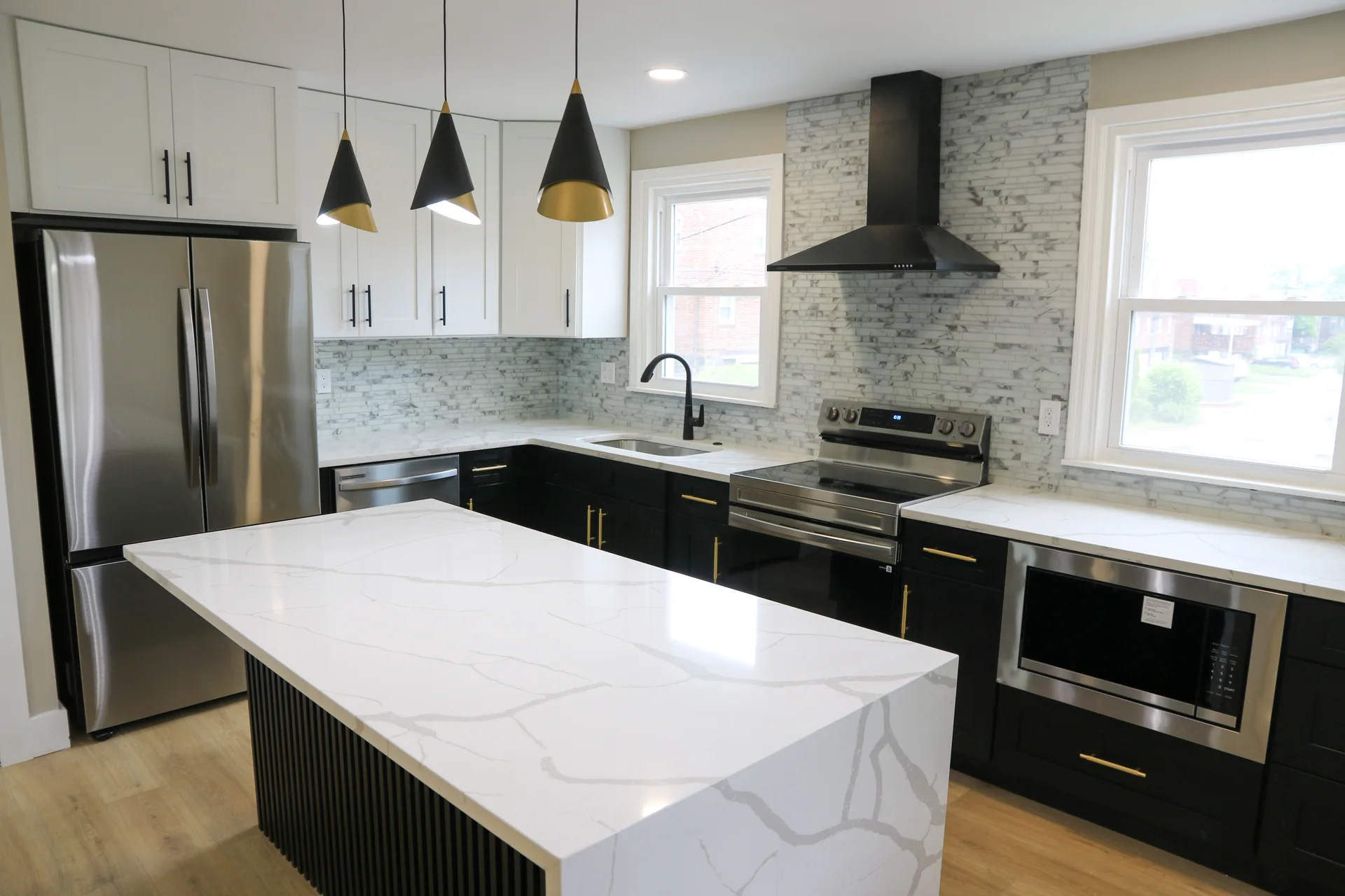 Calacatta quartz waterfall island with black fluted base and matte black hood