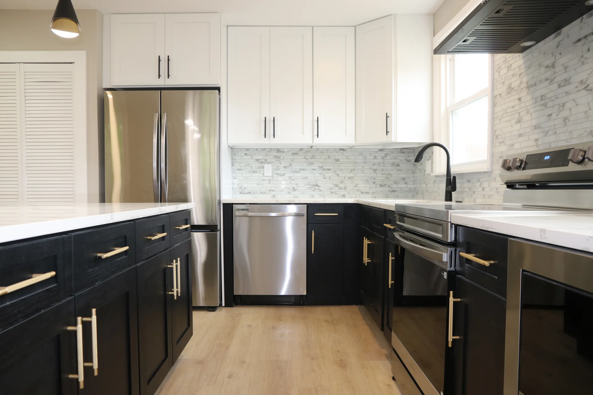 Two-tone kitchen with black lowers, white uppers, and gold hardware
