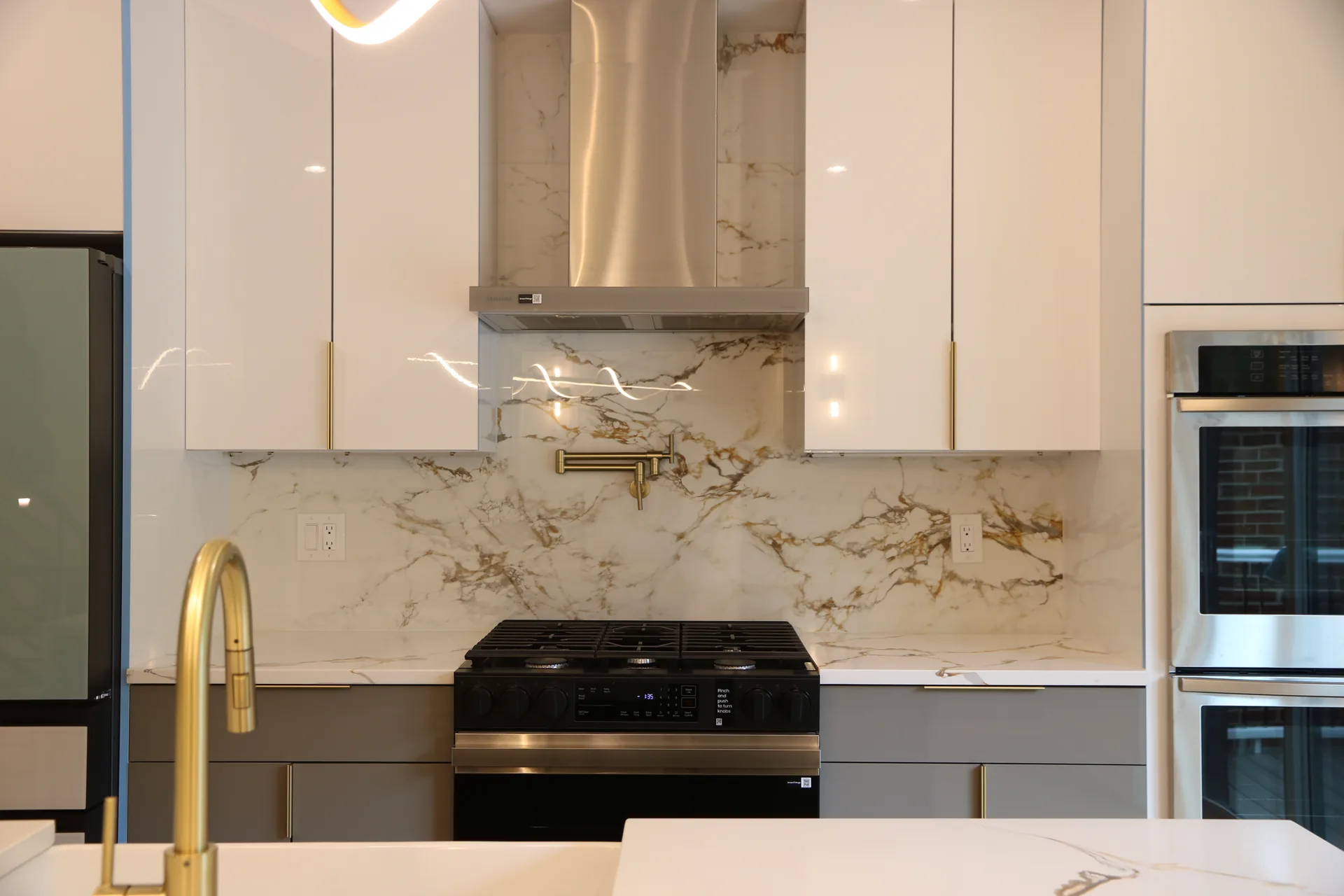 Gold-veined marble backsplash with stainless hood and two-tone cabinets