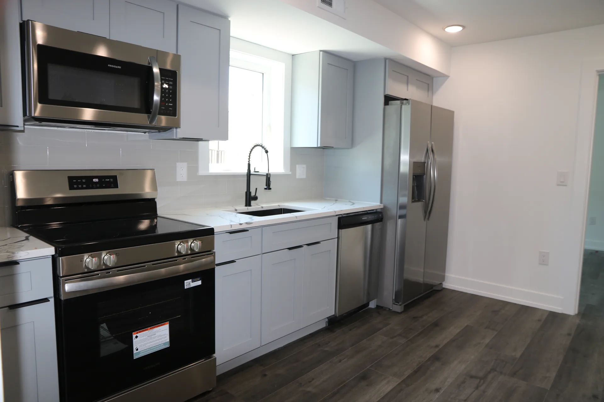 White kitchen unit with quartz counters and stainless appliances