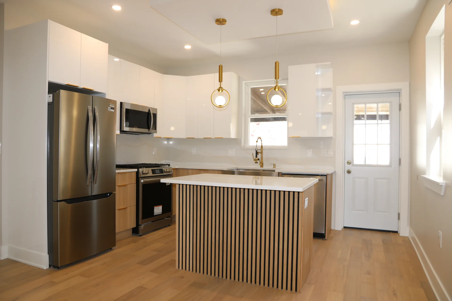 Glossy white kitchen with fluted wood island and gold pendants