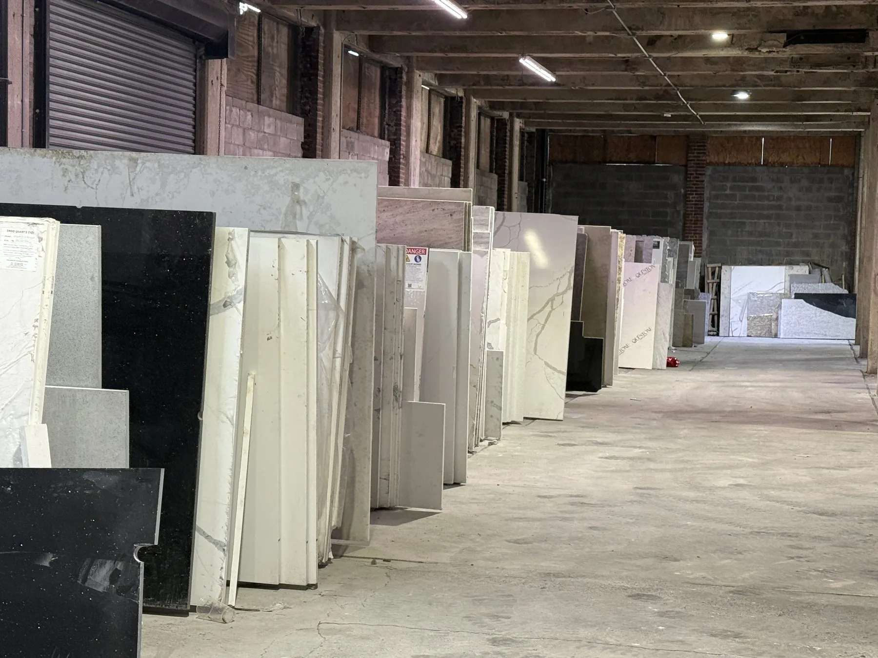 Rows of full-size granite, quartz, and marble slabs at the UMG warehouse